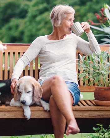 Older woman sitting on a bench drinking coffee